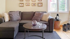 A living room with a sectional sofa, a round coffee table, and a window with a view of greenery. - 8 Person Holiday Home in Brottby-by Traum (Brottby)