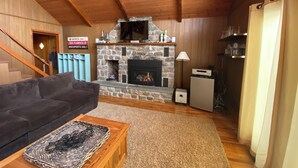 A cozy living room with a stone fireplace, a dark sofa, and a wooden coffee table. - Eat, Sleep, Ski. Repeat.  (Lake Harmony)