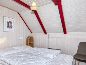 A bedroom with a bed, a chair, a wall-mounted lamp, a framed picture, and a sloped ceiling with exposed beams. - 6 Person Holiday Home in Thisted (Thisted)