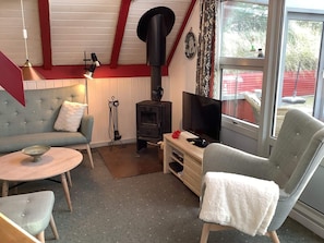 A cozy living room with a sofa, a chair, a small table, a fireplace, and a television.