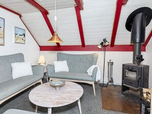A cozy living room with a sofa, a round coffee table, a fireplace, and a hanging lamp. - 6 Person Holiday Home in Thisted (Thisted)