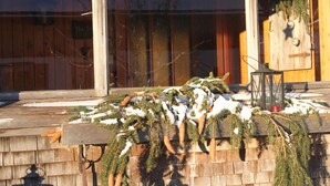 A wooden deck with snow-covered pine branches and a star ornament. - Holiday Home Geser Comfortable Vacation Home (Schnepfau)