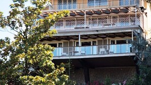 A multi-story building with balconies, outdoor seating, and a stone facade. - Belvilla by OYO Villa Teodora (Anguillara Sabazia)