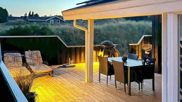 Una terrazza esterna con zona salotto coperta, un tavolo e sedie.