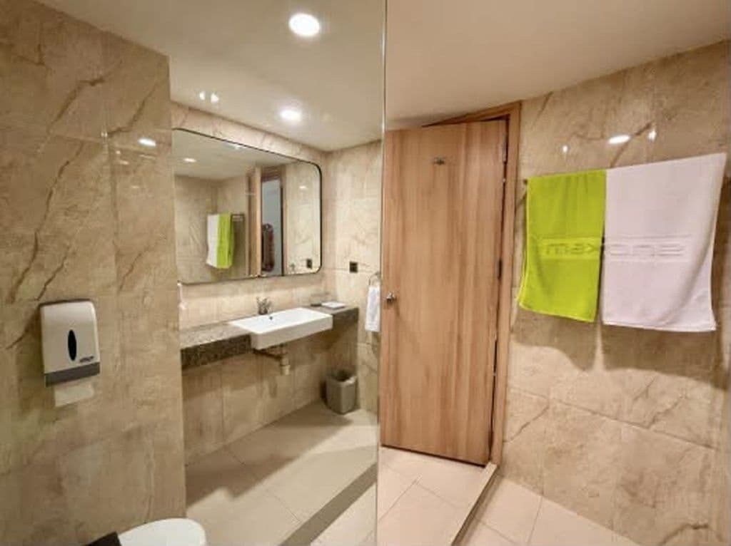 A bathroom with a marble wall, a wooden door, a sink, and a mirror.