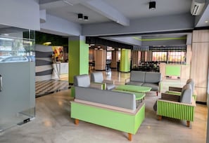 Un espacio interior moderno con zonas de estar, una escalera a la vista y un panel de vidrio.