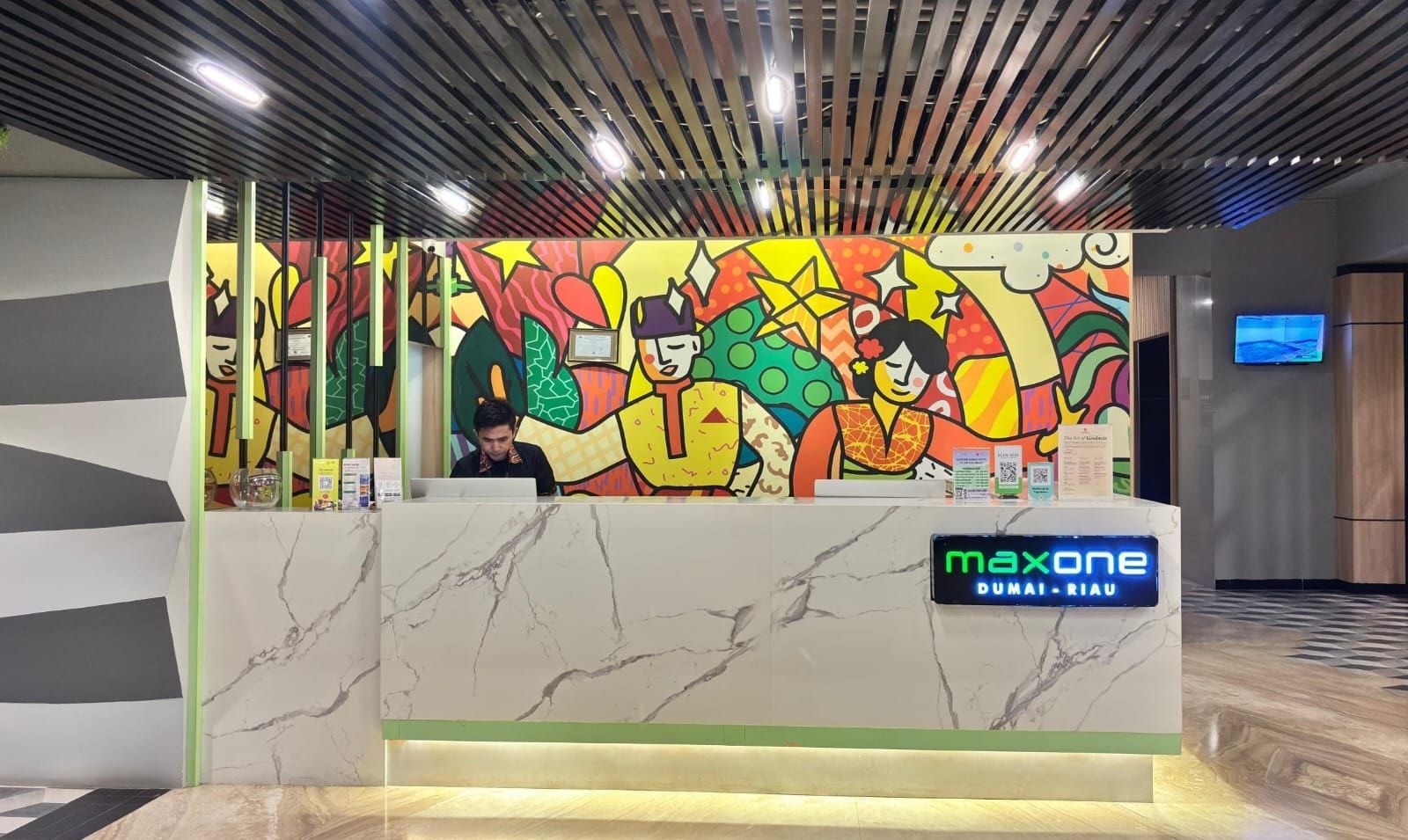 A reception desk with a colorful mural, a marble counter, and a digital display.