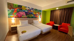 A hotel room with two beds, a colorful mural, a red chair, and a small table. - MaxOne Dumai (Dumai)