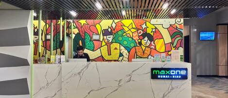Una reception con un murale colorato, un bancone in marmo e un display digitale.