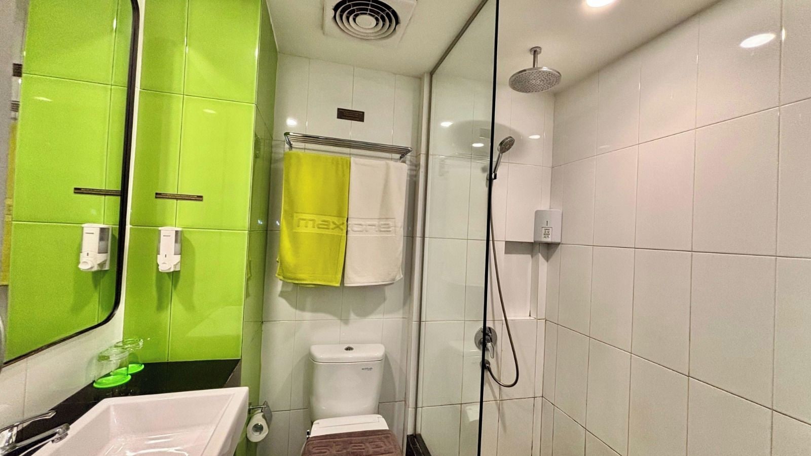 Ein Badezimmer mit grüner Wand, Toilette, Dusche und Waschbecken.