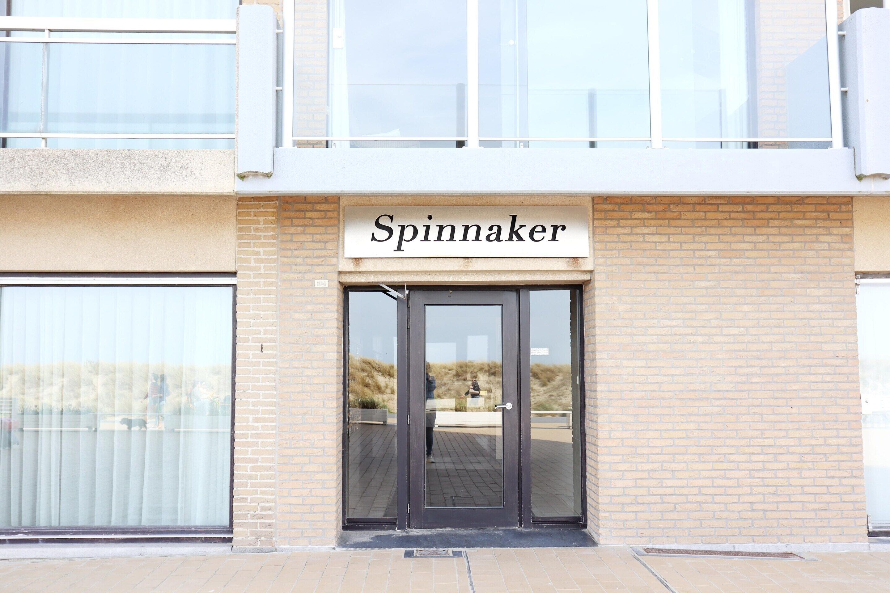 A building with a sign reading "Spinnaker" above a door.