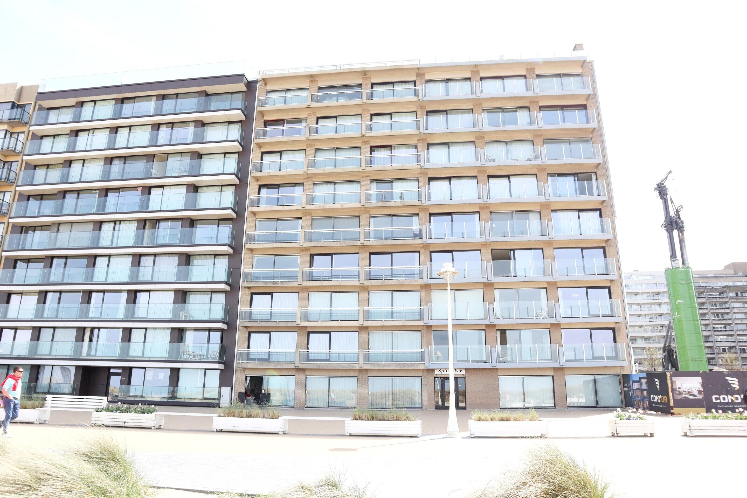 A multi-story building with a modern architectural design, featuring balconies and large windows.
