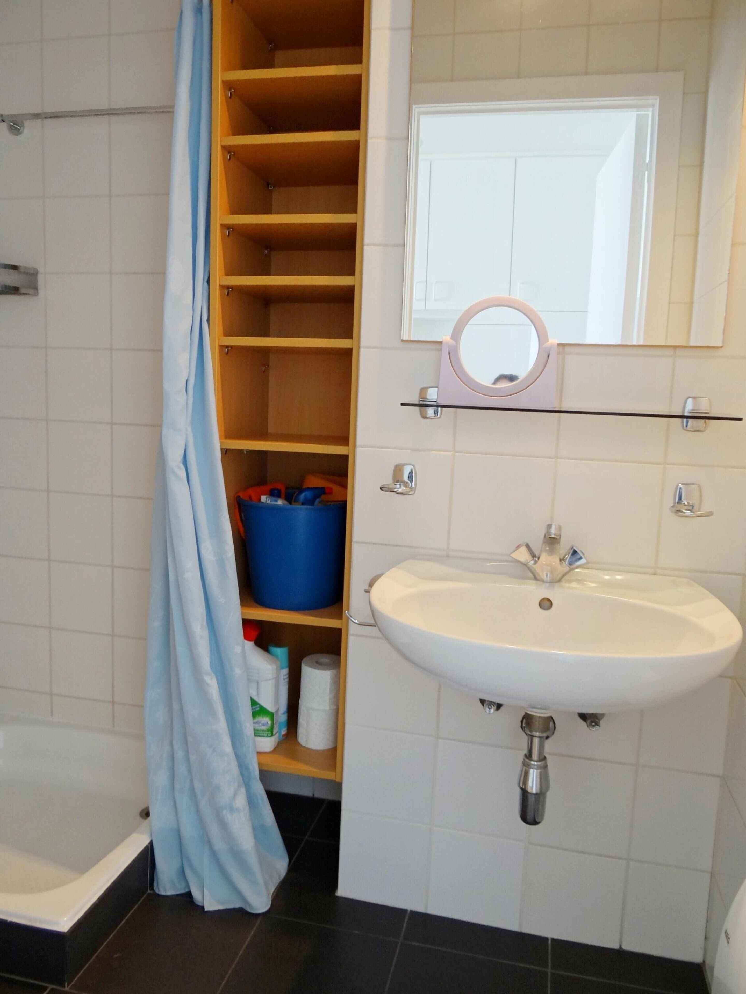 A bathroom with a white sink, a mirror, and a shower area.