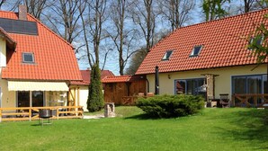 En bostadsfastighet med ett rött tegeltak, en täckt uteplats och en välskött gräsmatta.