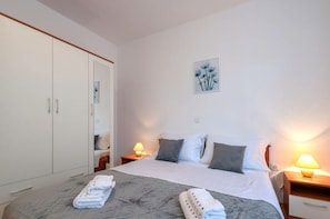 A hotel room with a large bed, two bedside tables with lamps, a wardrobe, and a framed artwork on the wall. - Andrea Comfortable Holiday Residence (Marcana)
