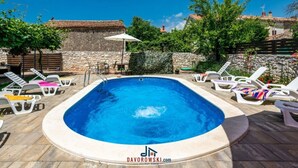 A swimming pool with lounge chairs and a stone wall in the background. - Andrea Comfortable Holiday Residence (Marcana)