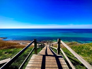 A wooden staircase leading to a beach with clear blue water. - 4 Star Holiday Home in Tisvildeleje (Tisvildeleje)
