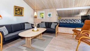 Ett mysigt vardagsrum med en mörkgrå soffa, ett soffbord i trä och en brun läderfåtölj.