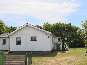 A white single-story building with a gabled roof, a small porch, and a flag.