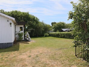 A fenced yard with a white building, a flag, and a hedge.