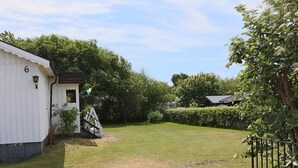 Ein von einer Hecke umgibendes Grundstück mit einem weißen Gebäude, einer Flagge und einem Baum.