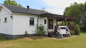 A single-story white building with a dark roof, a porch, and a small outdoor seating area. - 4 Star Holiday Home in Traslovslage (Träslövsläge)