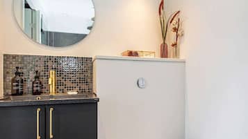 A bathroom with a dark countertop, a round mirror, and a white wall.