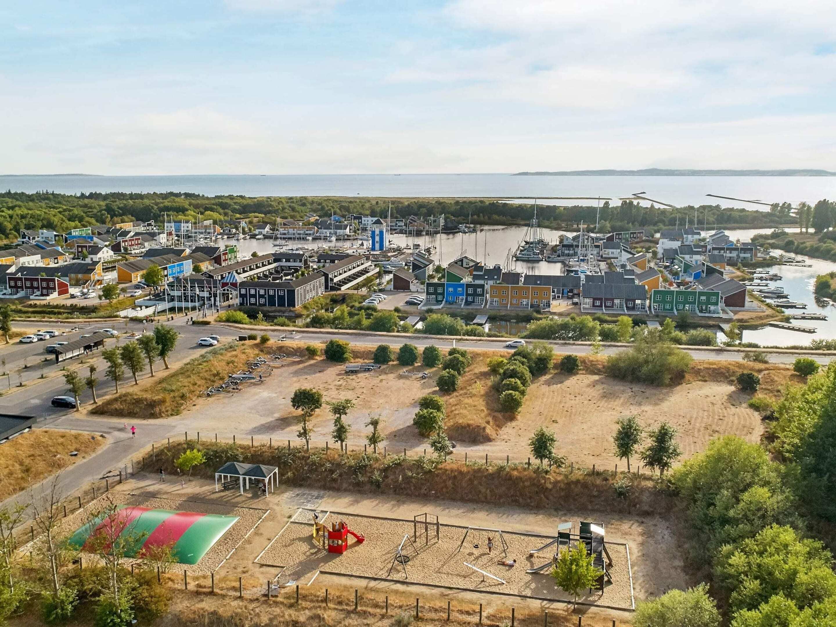 Un pueblo costero con un puerto deportivo, zonas de arena y un parque infantil.