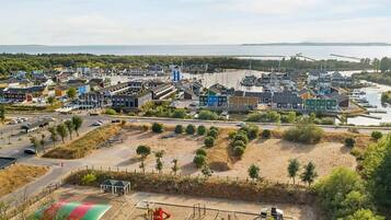Un pueblo costero con un puerto deportivo, zonas de arena y un parque infantil.