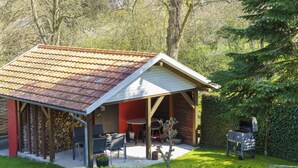 A covered outdoor area with a tiled roof, wooden beams, and a barbecue grill. - Holiday Apartment Sauer Large (Varel)
