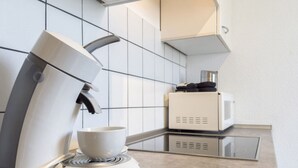 A modern kitchen with a coffee machine, a microwave, and a cup on the counter. - Holiday Apartment Sauer Large (Varel)