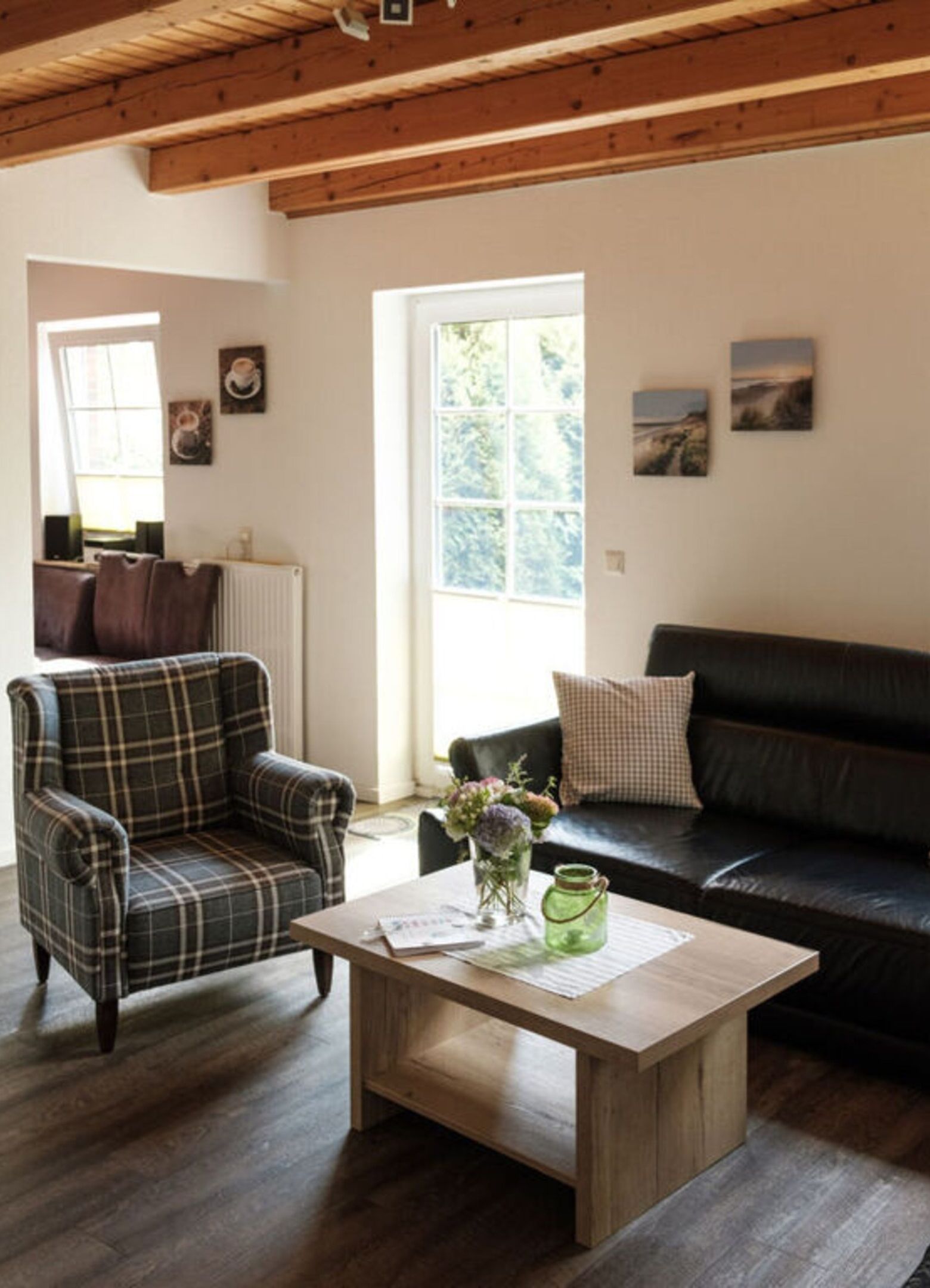 Un salon chaleureux avec un fauteuil à carreaux, un canapé en cuir foncé et une table basse en bois.