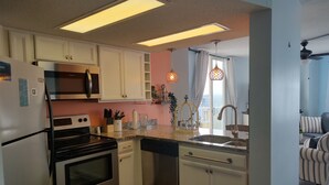 A modern kitchen with white cabinets, stainless steel appliances, and a granite countertop. - Top floor condo in N. Topsail Beach. Views of the beach & Intracoastal Waterway! (North Topsail Beach)
