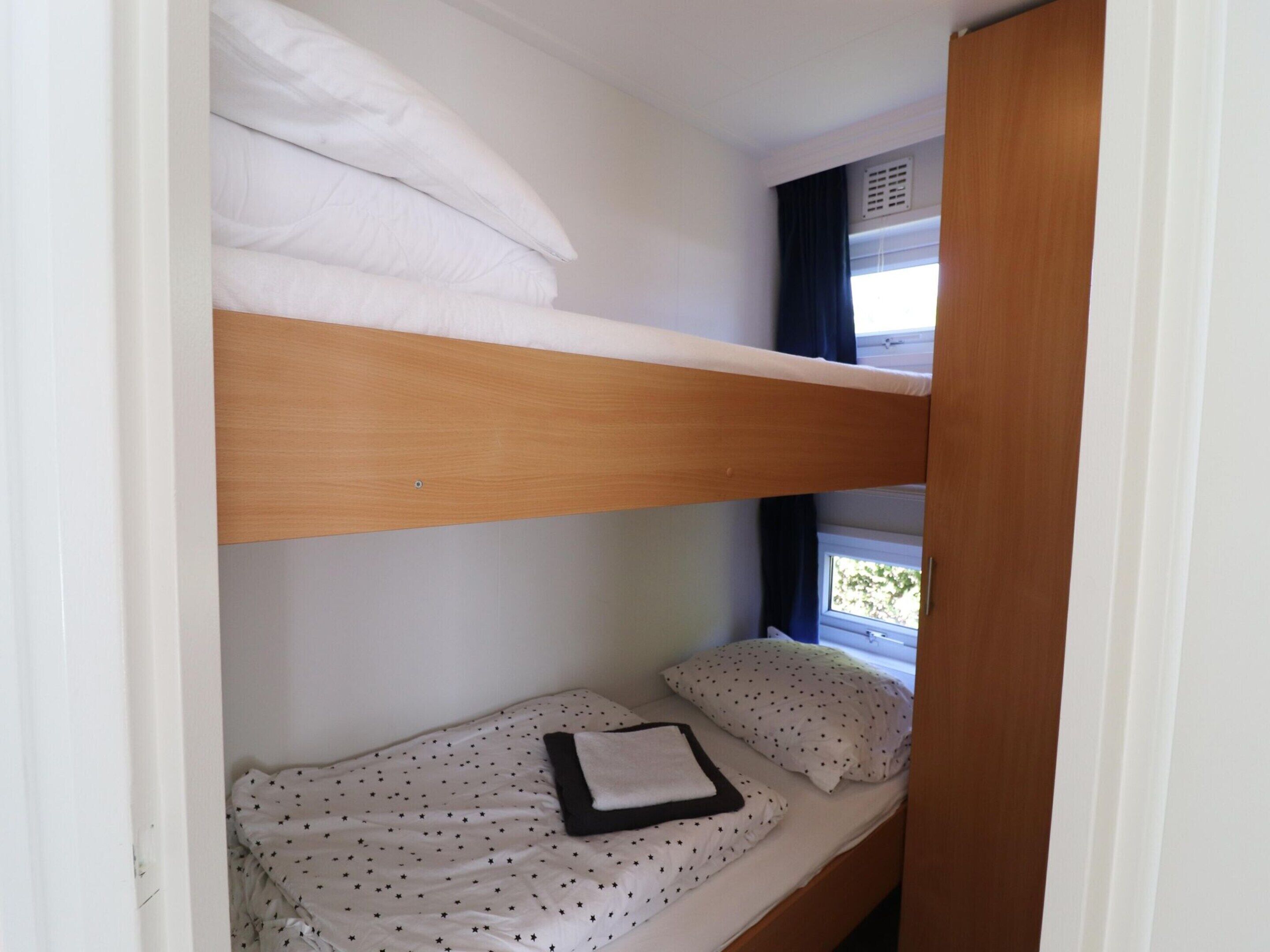 A bunk bed with white bedding and a star-patterned sheet on the lower bunk.