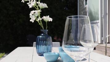 A table with a clear glass, a vase with flowers, and blue bowls.