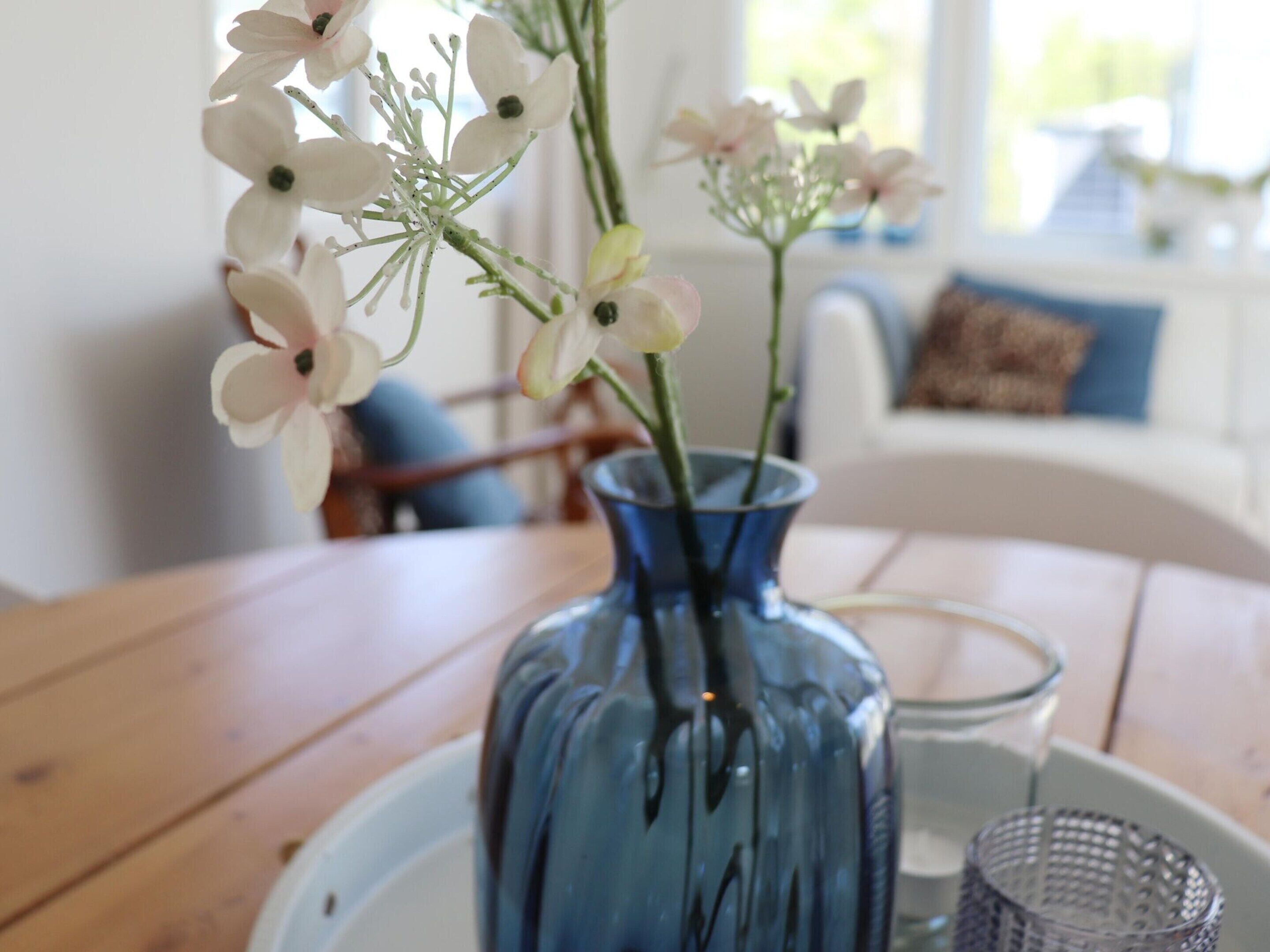 A blue vase with flowers on a wooden table.
