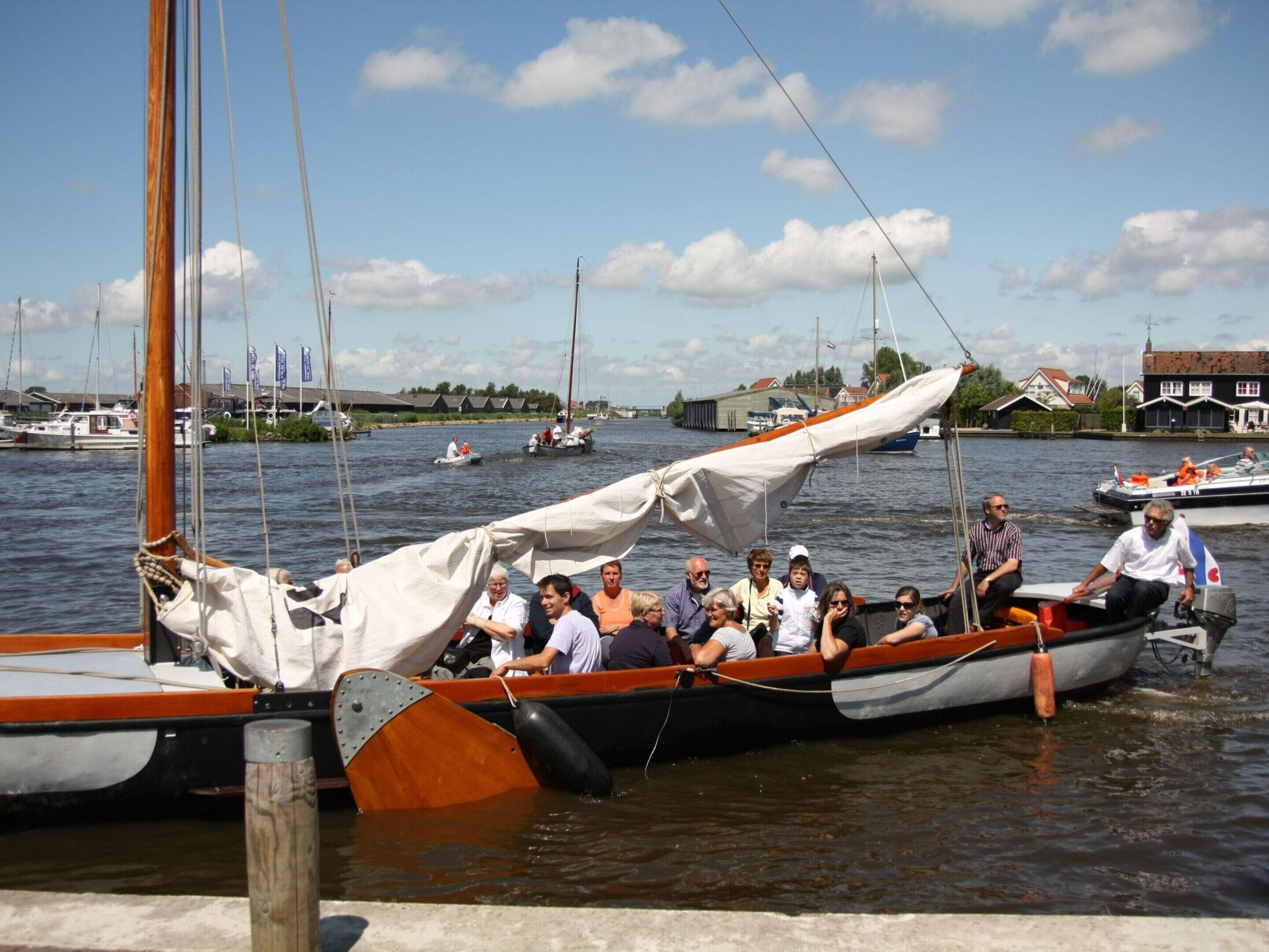 A group of people on a small boat at a marina with other boats and buildings in the background.
