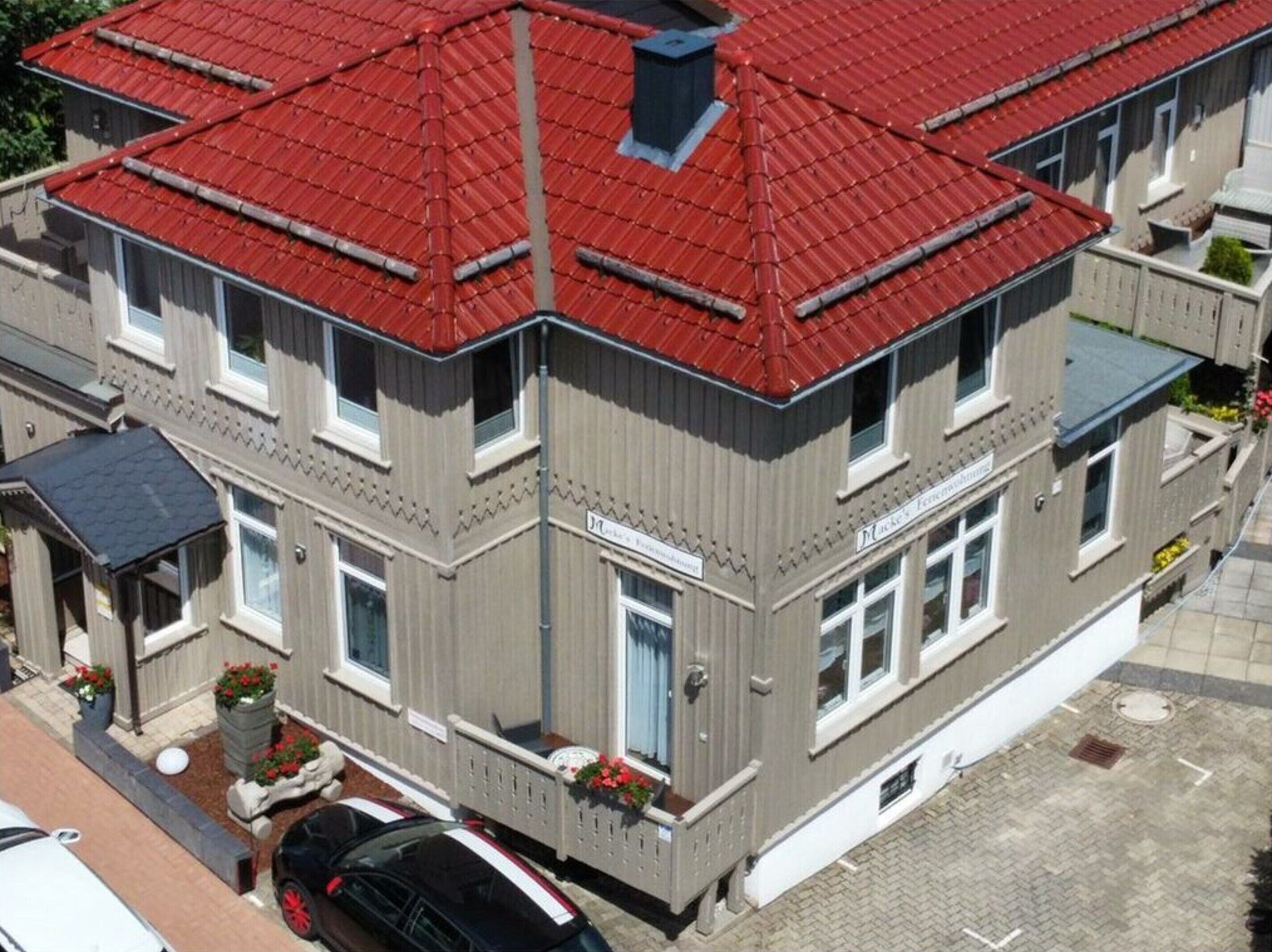Un bâtiment à deux étages, avec un toit rouge, de nombreuses fenêtres et une enseigne indiquant qu’il s’agit d’un hôtel.