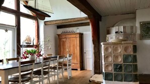 A dining area with a wooden table and chairs, a wooden cabinet, and a decorative stove. - Warft Simmerdeis 2 Comfortable Holiday Residence (Oldenswort)