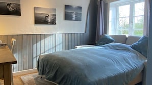 A bedroom with a bed, a window with curtains, and three wall-mounted pictures. - Warft Simmerdeis 2 Comfortable Holiday Residence (Oldenswort)