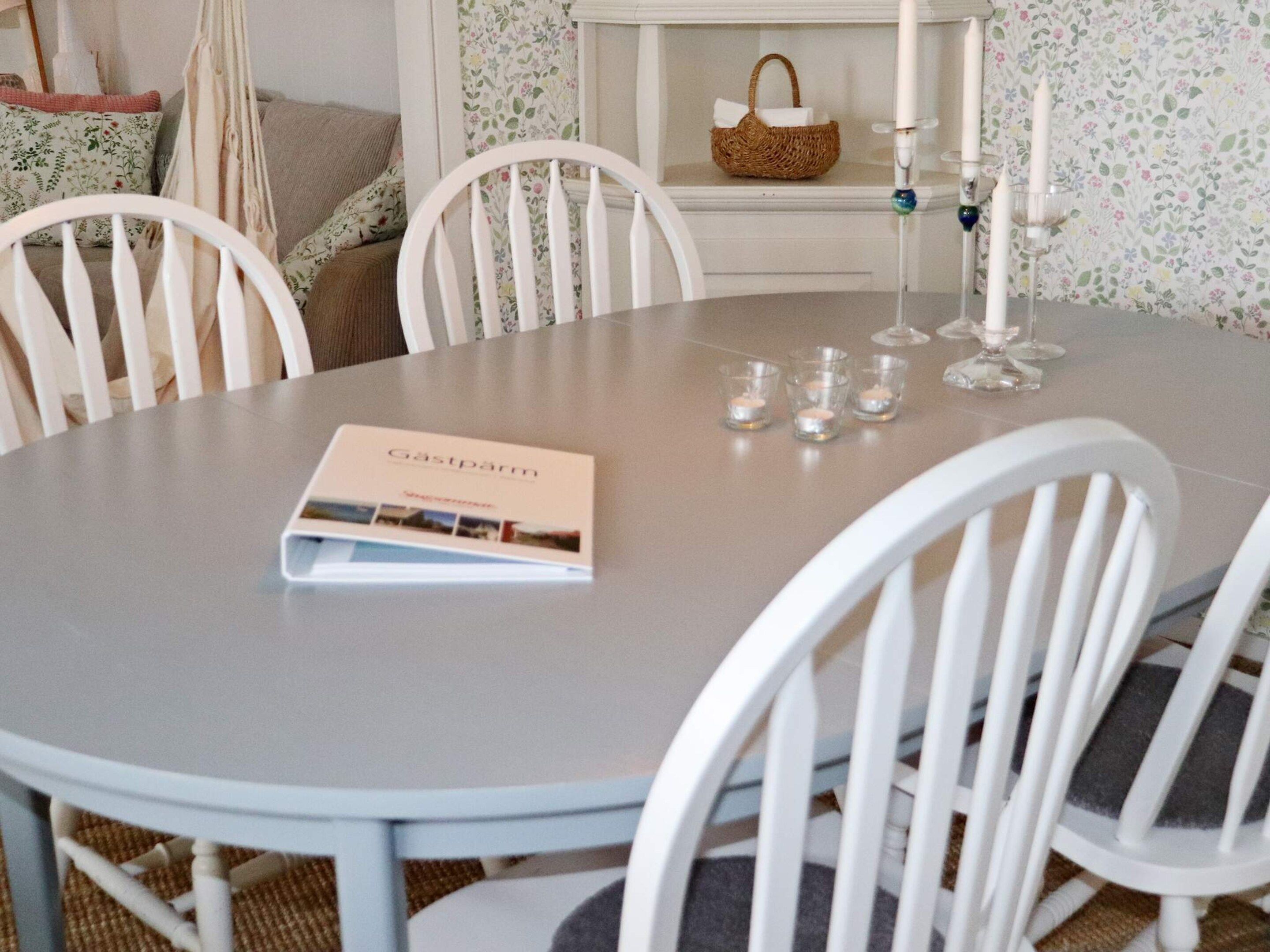 Una mesa redonda para comer con un folleto, velas y copas.