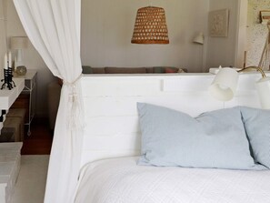 A bedroom with a white bed, striped pillows, a hanging light fixture, and a bedside table with a lamp. - 4 Person Holiday Home in Varberg (Varberg)