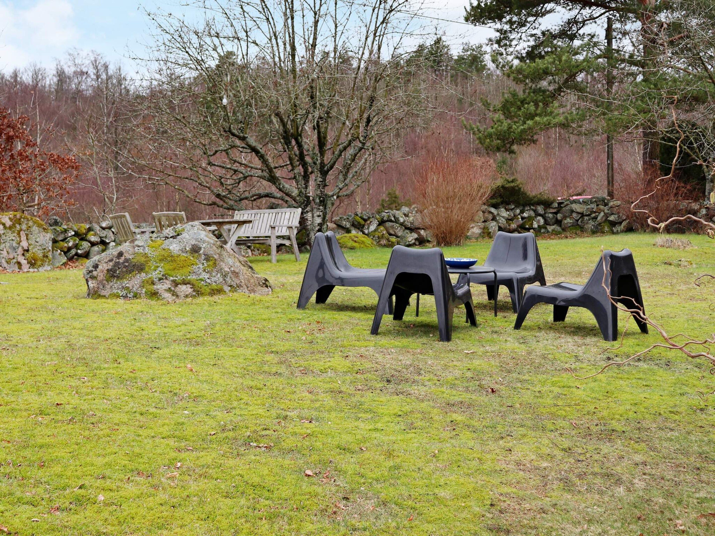 An outdoor seating area with a table and chairs, surrounded by a grassy field and trees.