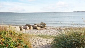 A beach with a clear sky, calm sea, and a rocky outcrop. - 4 Person Holiday Home in Varberg (Varberg)