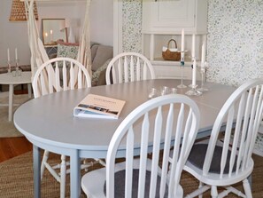 A dining area with a round table, white chairs, and a book titled 'Gästspår'. - 4 Person Holiday Home in Varberg (Varberg)