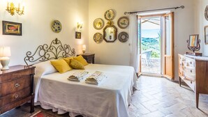 Ein Schlafzimmer mit Bett, Nachttischen, einem Schminktisch und Blick ins Freie.