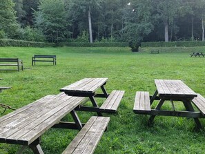 A grassy outdoor area with picnic tables and benches. - Luxury Spa Retreat in Lolland - By Traum Ferienwohnungen (Nakskov)
