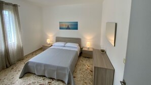 Une chambre à coucher avec un lit, deux tables de chevet avec des lampes, un tableau au mur et une porte.