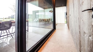 A modern interior with a glass door leading to an outdoor patio area. - Maison Lodge 5 Modern and Luxuriously Finished Near Somme-leuze (Somme-Leuze)