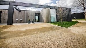 A modern building with a gravel driveway, a wooden fence, and a metal canopy. - Maison Lodge 5 Modern and Luxuriously Finished Near Somme-leuze (Somme-Leuze)